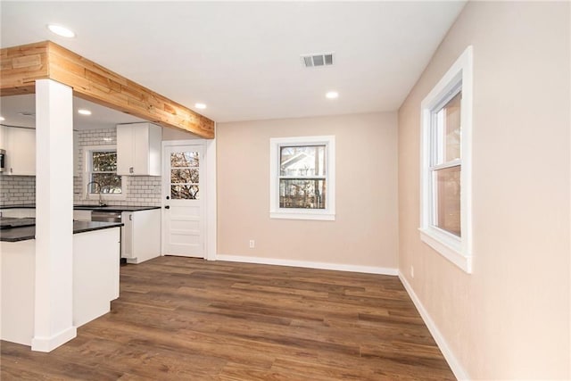 bar with visible vents, dark wood-type flooring, baseboards, decorative backsplash, and a sink