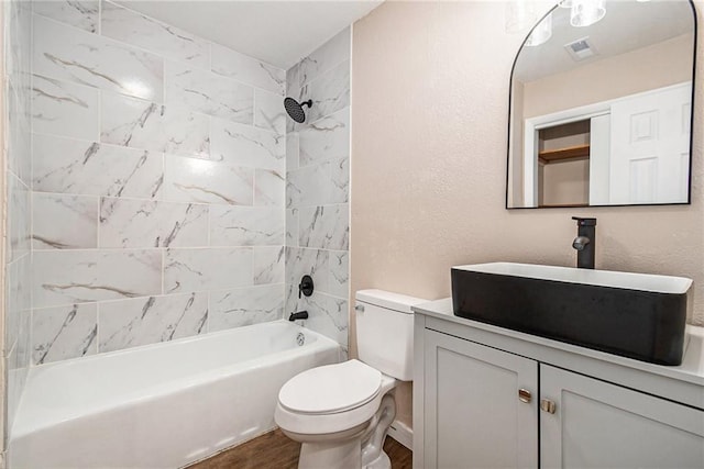 bathroom featuring visible vents, toilet, wood finished floors, tub / shower combination, and vanity