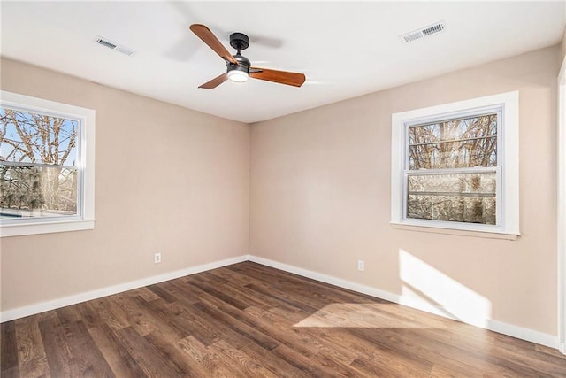 empty room featuring dark wood-type flooring, baseboards, and visible vents