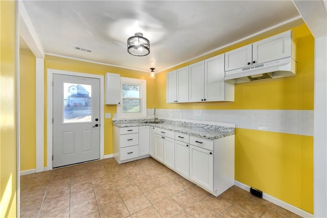 kitchen featuring light stone countertops, sink, light tile patterned flooring, backsplash, and white cabinets