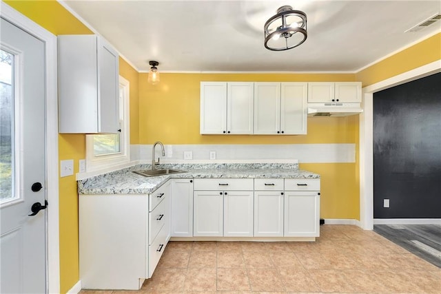 kitchen featuring white cabinets, light stone counters, sink, and a wealth of natural light