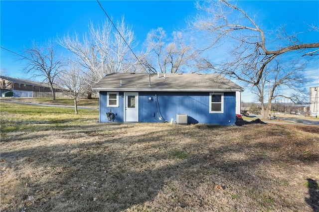 back of property with central AC and a lawn