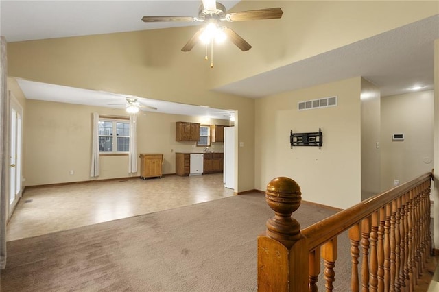 unfurnished living room with carpet flooring, plenty of natural light, lofted ceiling, and ceiling fan