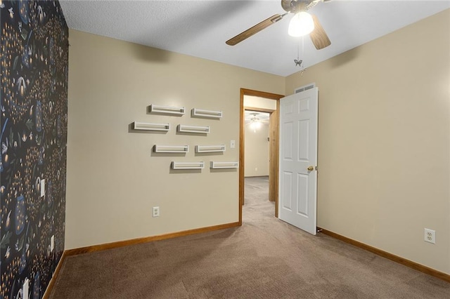 empty room featuring ceiling fan and light colored carpet