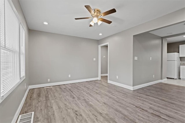 empty room featuring a healthy amount of sunlight, ceiling fan, and light hardwood / wood-style floors