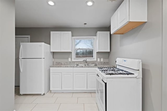 kitchen with white cabinetry, light stone countertops, white appliances, and sink