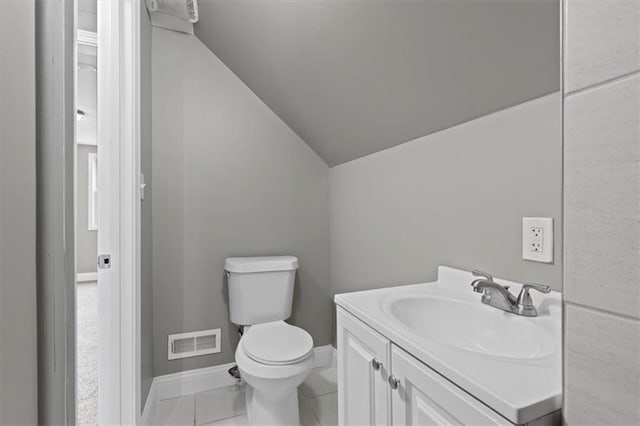 bathroom with tile patterned flooring, vanity, toilet, and lofted ceiling