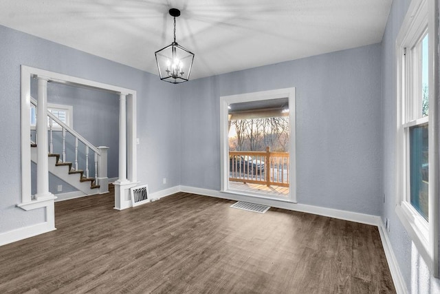 empty room with dark wood-type flooring and a chandelier