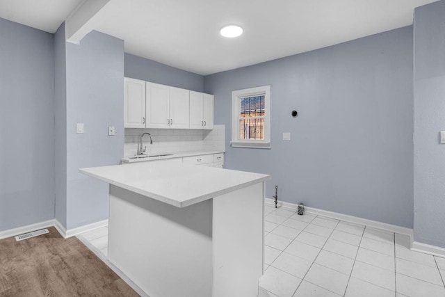 kitchen with a center island, backsplash, white cabinets, sink, and light tile patterned floors