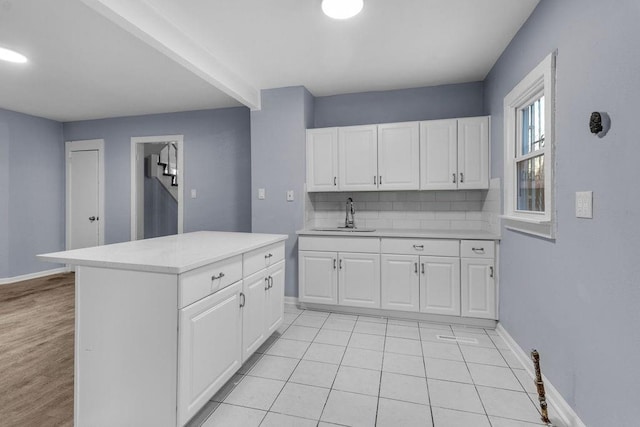 kitchen with white cabinets, backsplash, light tile patterned flooring, and sink