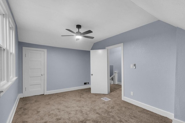 unfurnished room featuring light colored carpet, vaulted ceiling, and ceiling fan