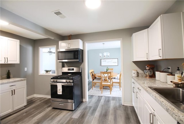 kitchen with visible vents, white cabinets, appliances with stainless steel finishes, wood finished floors, and a sink