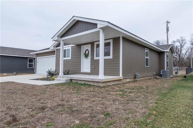 view of front of house with a porch, cooling unit, a garage, and a front lawn