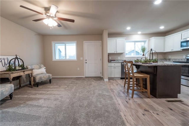 kitchen with a kitchen breakfast bar, white cabinetry, a healthy amount of sunlight, and stainless steel appliances