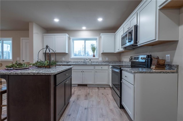 kitchen with light stone countertops, white cabinetry, and stainless steel appliances