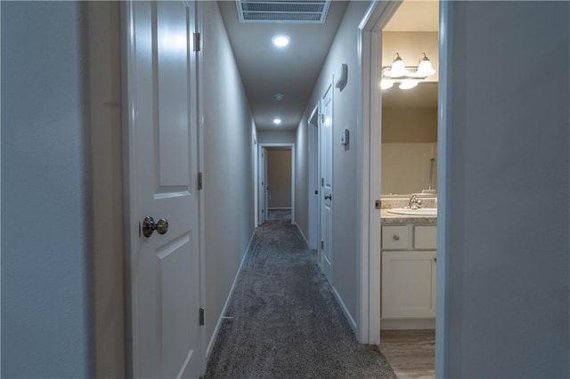 corridor featuring dark colored carpet and sink