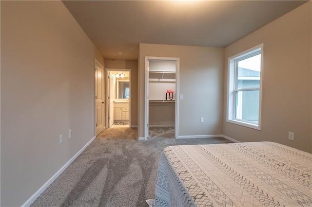 unfurnished bedroom featuring carpet, a walk in closet, connected bathroom, and a closet