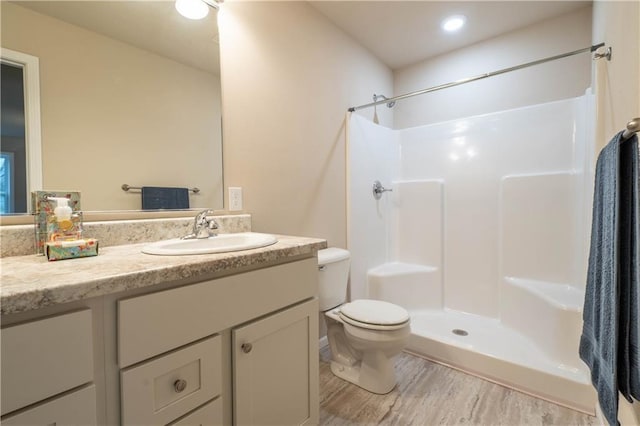 bathroom with a shower, vanity, wood-type flooring, and toilet