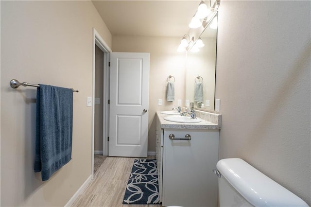 bathroom featuring hardwood / wood-style floors, vanity, an inviting chandelier, and toilet