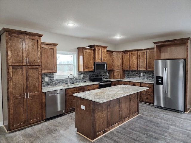 kitchen featuring hardwood / wood-style floors, sink, backsplash, a center island, and stainless steel appliances