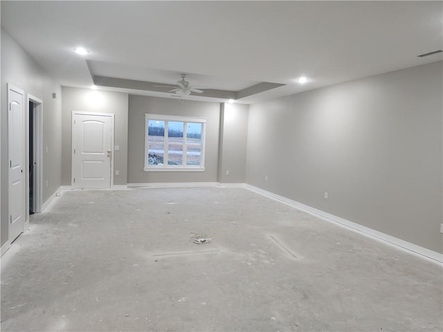 unfurnished room with ceiling fan and a tray ceiling