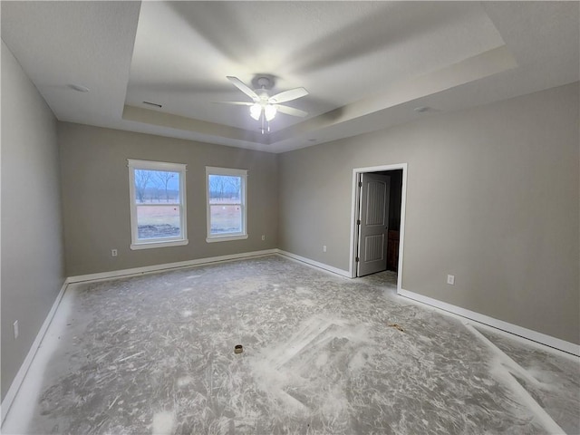 unfurnished room featuring ceiling fan and a raised ceiling