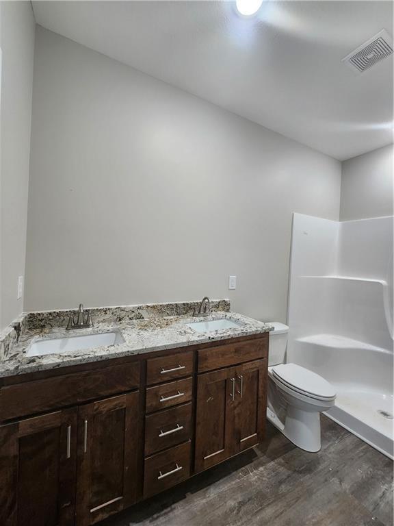 bathroom with vanity, toilet, hardwood / wood-style floors, and a shower