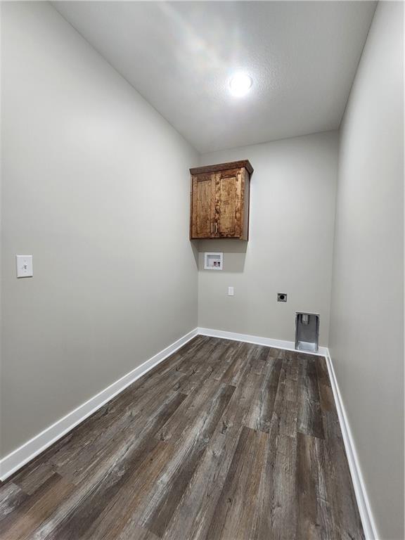 clothes washing area featuring dark wood finished floors, hookup for a washing machine, cabinet space, hookup for an electric dryer, and baseboards