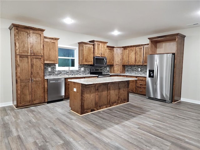 kitchen featuring stainless steel appliances, a kitchen island, light wood finished floors, and tasteful backsplash