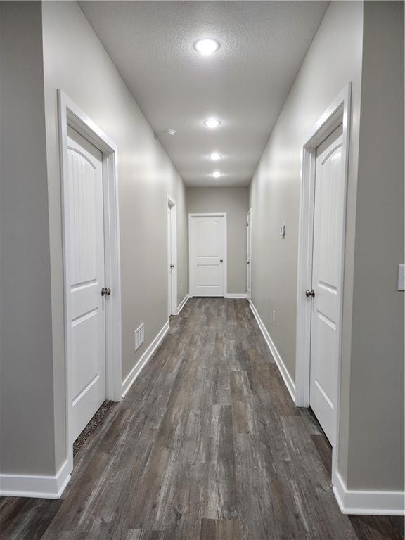 hall with dark wood-style floors and baseboards