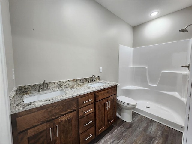 bathroom with toilet, walk in shower, a sink, and wood finished floors