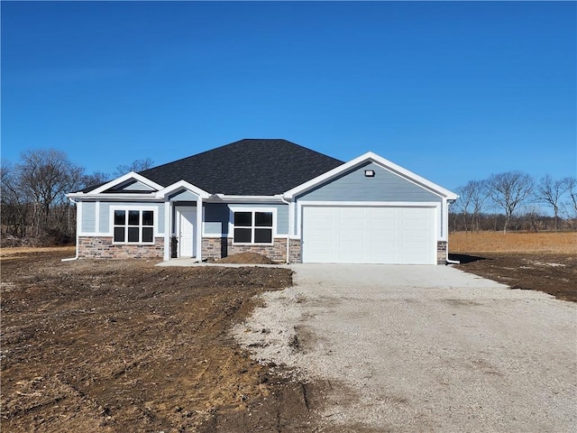 view of front facade featuring a garage, driveway, roof with shingles, and stone siding