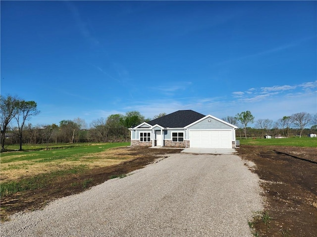 ranch-style home with an attached garage, driveway, and stone siding
