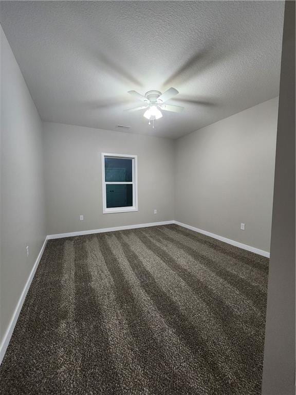 empty room featuring dark colored carpet, a textured ceiling, baseboards, and ceiling fan