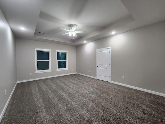 unfurnished room featuring a tray ceiling, carpet, baseboards, and ceiling fan