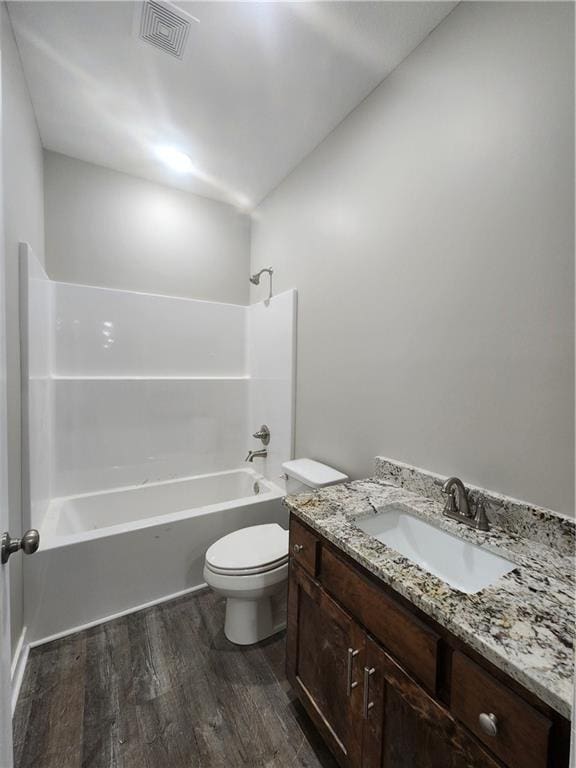 bathroom with bathing tub / shower combination, wood finished floors, visible vents, toilet, and vanity