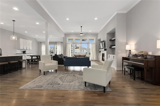 living room featuring crown molding, ceiling fan, dark hardwood / wood-style flooring, and built in shelves