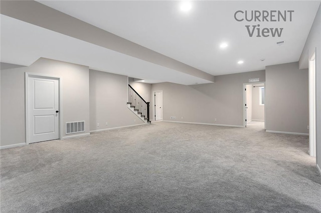 finished below grade area featuring visible vents, stairway, baseboards, and carpet floors