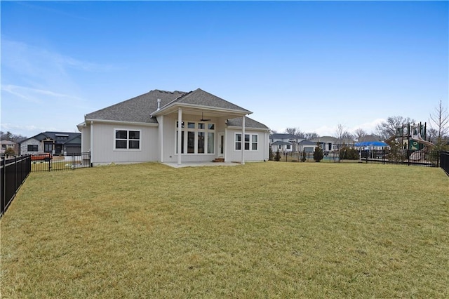 rear view of house with a lawn and a fenced backyard