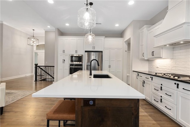 kitchen with a breakfast bar area, custom range hood, a sink, appliances with stainless steel finishes, and backsplash
