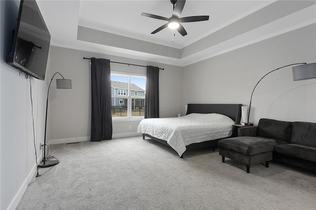 bedroom with carpet flooring, ceiling fan, a tray ceiling, baseboards, and ornamental molding