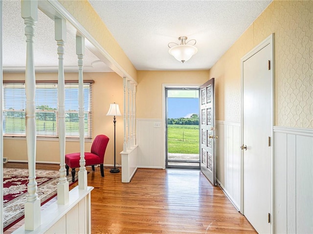 foyer entrance with light hardwood / wood-style floors and a textured ceiling