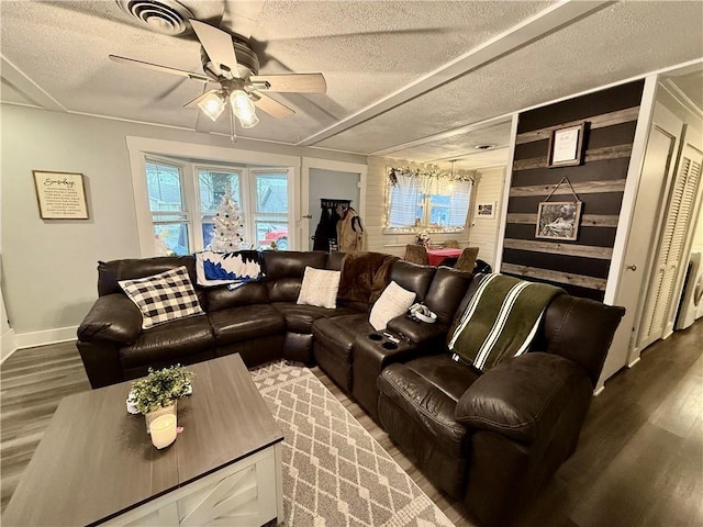 living room with dark hardwood / wood-style flooring, a textured ceiling, ceiling fan, and wood walls