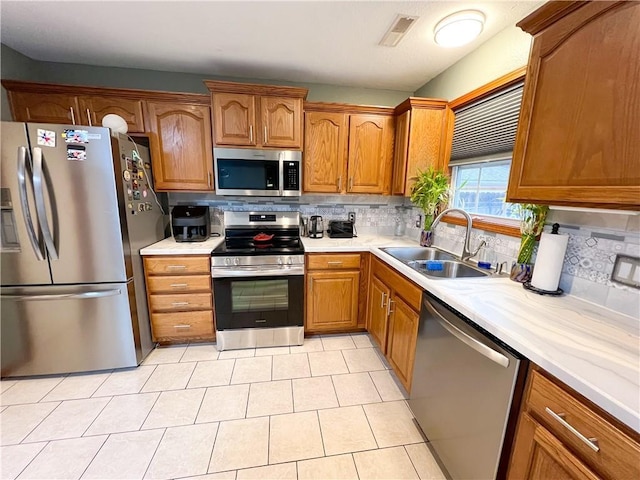 kitchen with light tile patterned flooring, backsplash, stainless steel appliances, and sink