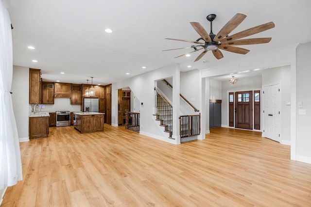 kitchen with pendant lighting, a center island, backsplash, ceiling fan, and stainless steel appliances