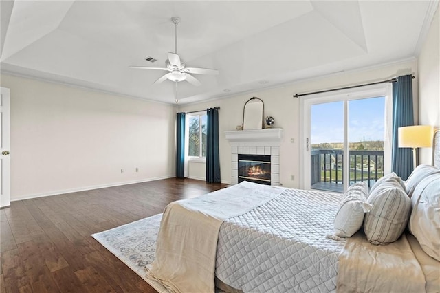 bedroom with ceiling fan, dark wood-type flooring, access to outside, and a tray ceiling