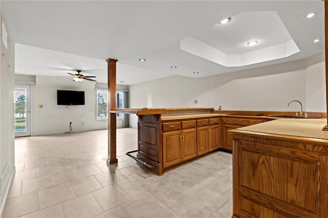 kitchen with a wealth of natural light, kitchen peninsula, sink, and ornate columns