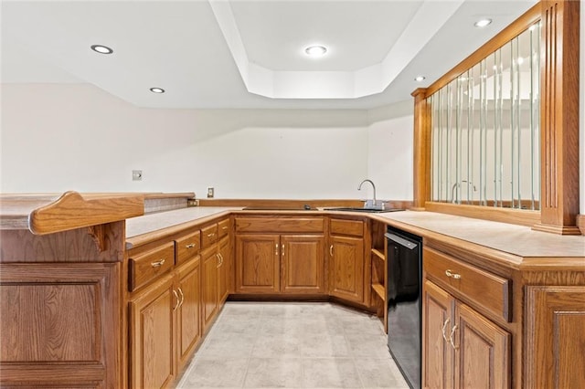 kitchen with a raised ceiling, fridge, sink, and kitchen peninsula