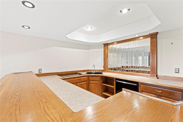 kitchen featuring black appliances, sink, and a tray ceiling