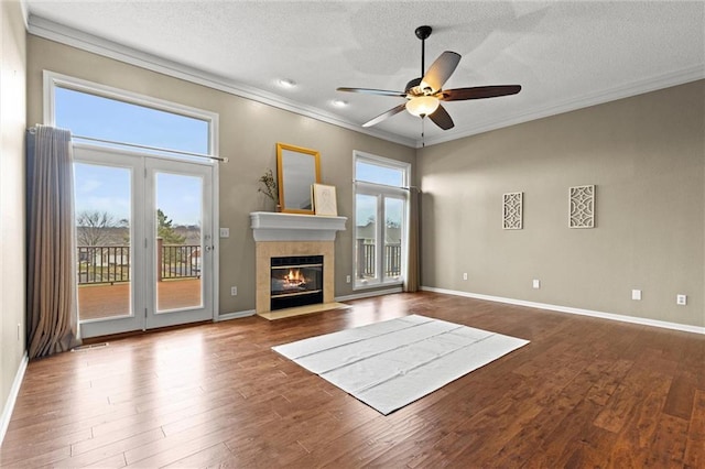 unfurnished living room featuring a textured ceiling, ceiling fan, crown molding, and a wealth of natural light